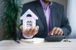 man holding mini house model